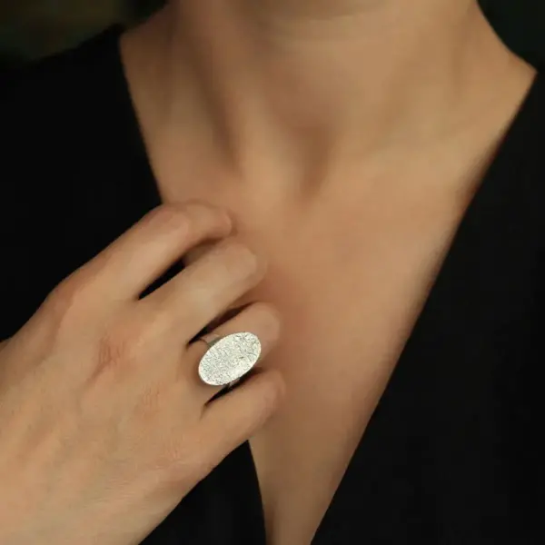 srebrny pierścionek owalny na palcu
